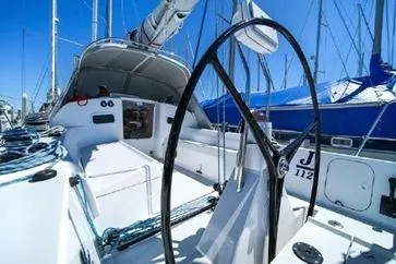 Slide: The Image of 2021 J Boats J/112E sailboat cockpit with steering wheel, docked under clear blue sky. - 21
