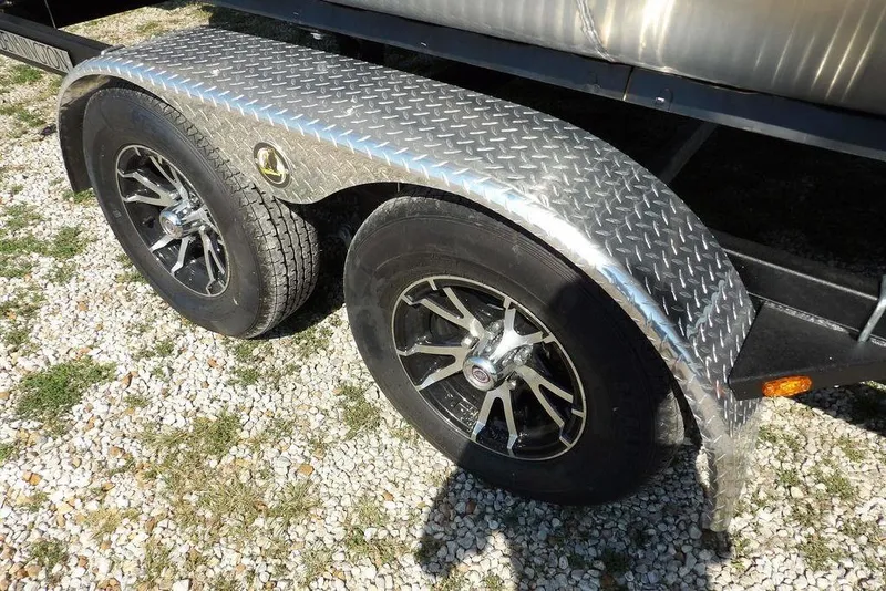 Slide: The Image of 2026 Bennington S Quad Bench 22 SSR trailer with dual wheels on gravel. - 43