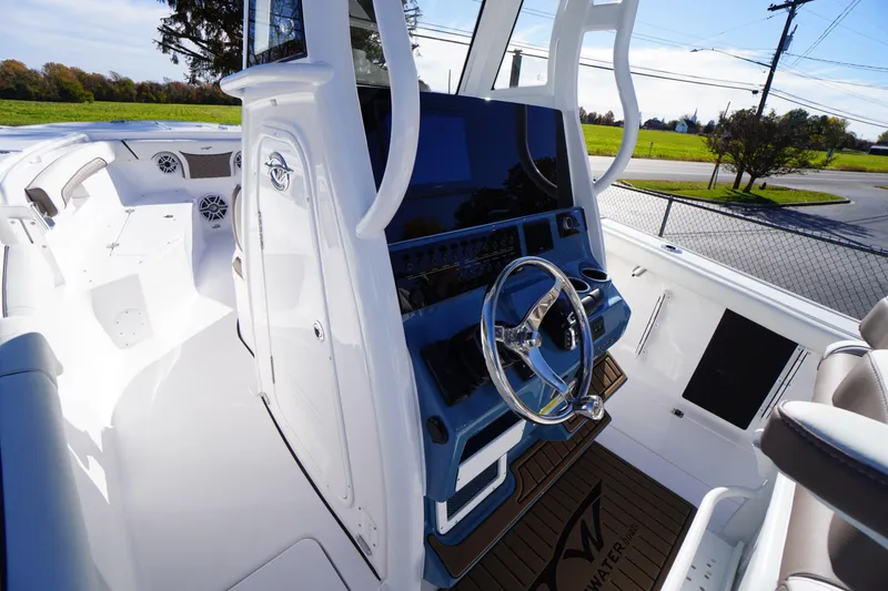 Slide: The Image of 2026 Tidewater 256 CC Adventure boat with blue T-top, parked outdoors. - 22
