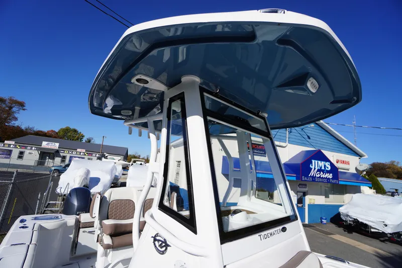 Slide: The Image of 2026 Tidewater 256 CC Adventure boat with blue T-top under clear sky. - 46