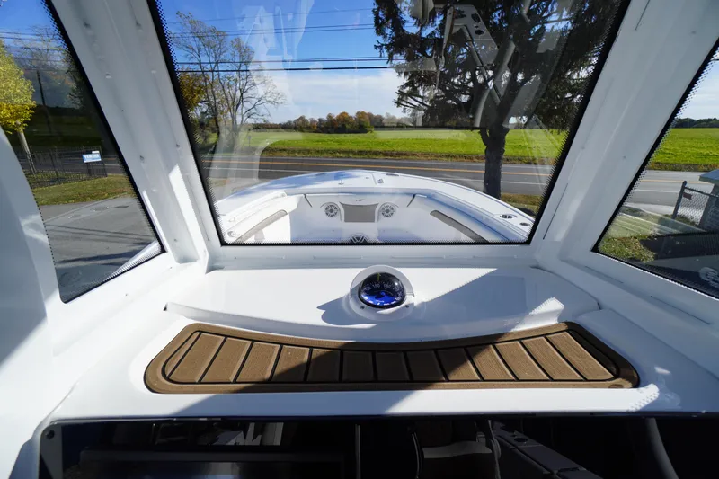 Slide: The Image of 2026 Tidewater 256 CC Adventure boat helm with clear windshield and scenic view. - 48