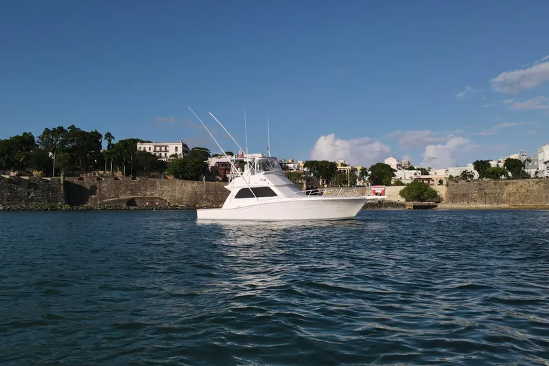 Slide: The Image of 1999 Viking 43 Convertible yacht on calm water near historic coastal town. - 2