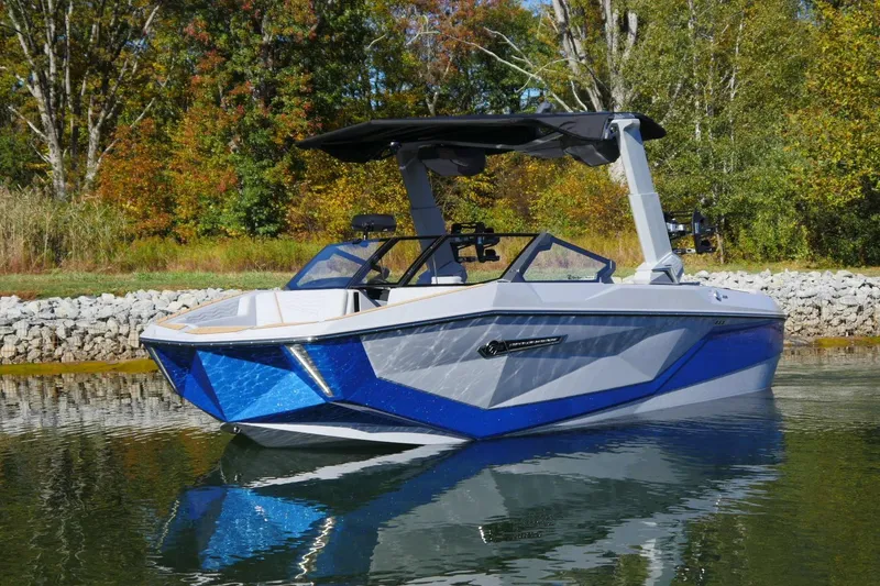 Slide: The Image of 2026 Nautique Super Air Nautique G23 boat on calm water, surrounded by autumn trees. - 16