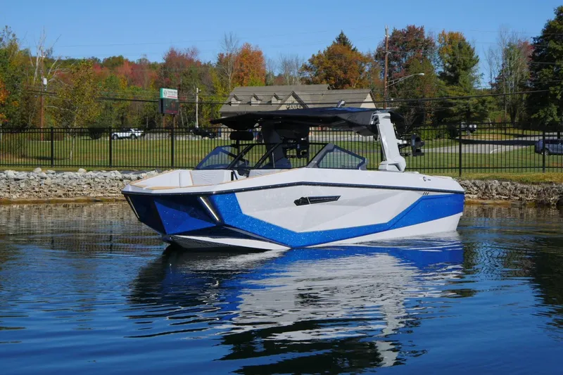 Slide: The Image of 2026 Nautique Super Air Nautique G23 boat on calm water, surrounded by autumn trees. - 17