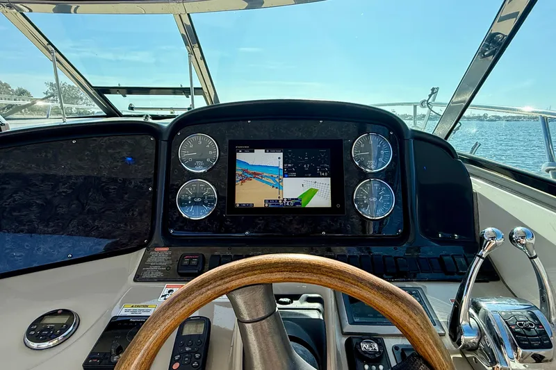Slide: The Image of 2008 Sea Ray 38 Sundancer helm with navigation display and gauges, overlooking water. - 12