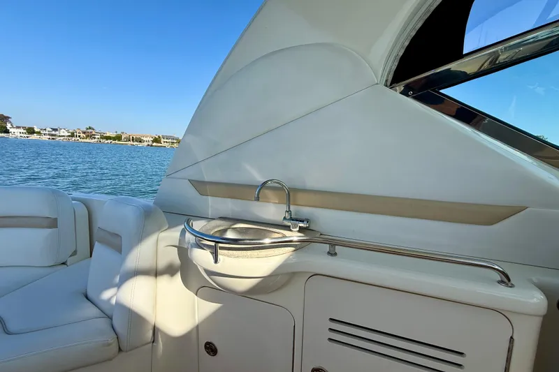 Slide: The Image of 2008 Sea Ray 38 Sundancer boat interior with sink and seating, overlooking water. - 26