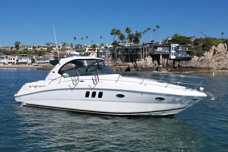 Slide: The Image of 2008 Sea Ray 38 Sundancer yacht cruising near coastal homes under clear blue skies. - 5