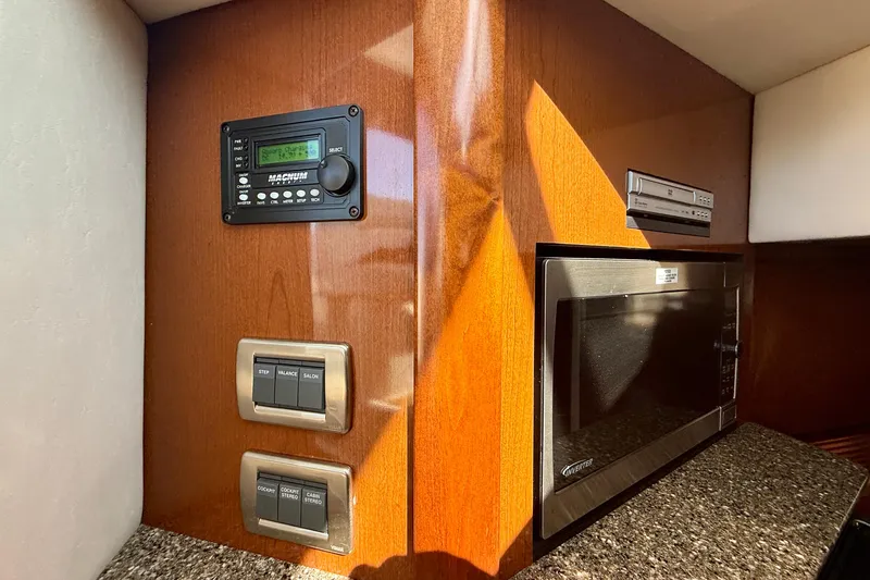 Slide: The Image of 2008 Sea Ray 38 Sundancer interior with microwave, control panel, and wood finish. - 54