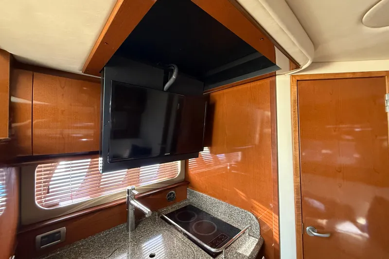 Slide: The Image of Interior of 2008 Sea Ray 38 Sundancer with TV, stove, and wooden cabinetry. - 56