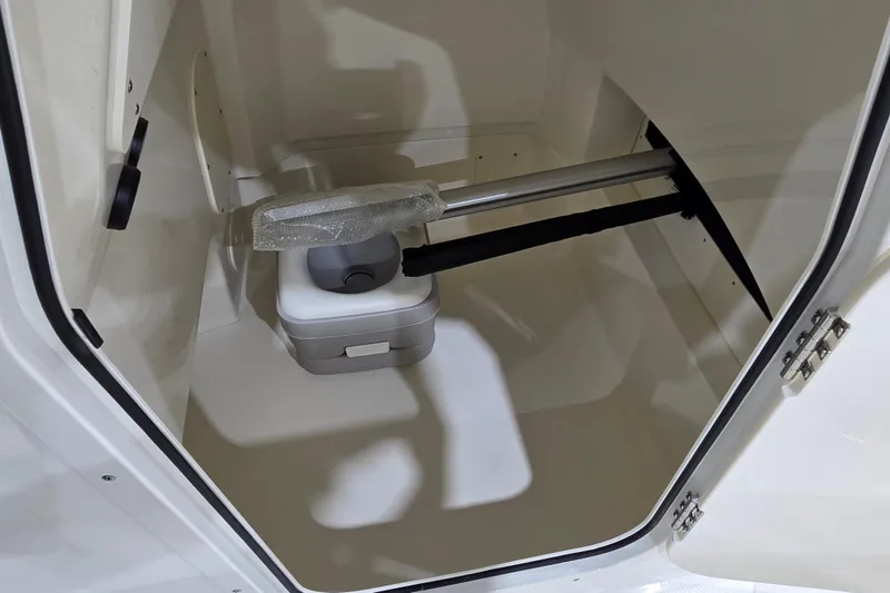 Slide: The Image of Storage compartment inside 2026 Boston Whaler 220 Dauntless boat, featuring a portable toilet. - 50