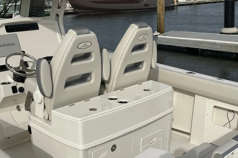 Slide: The Image of 2026 Sailfish 272 CC boat interior with dual seats and steering wheel at marina. - 11