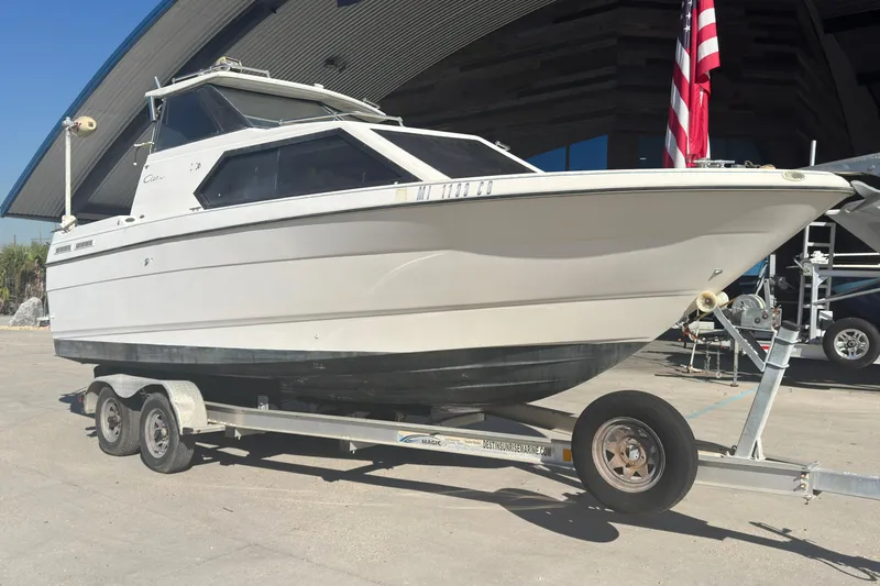 Slide: The Image of 1998 Bayliner 2452 Ciera Express boat on trailer, parked outdoors near a building. - 23