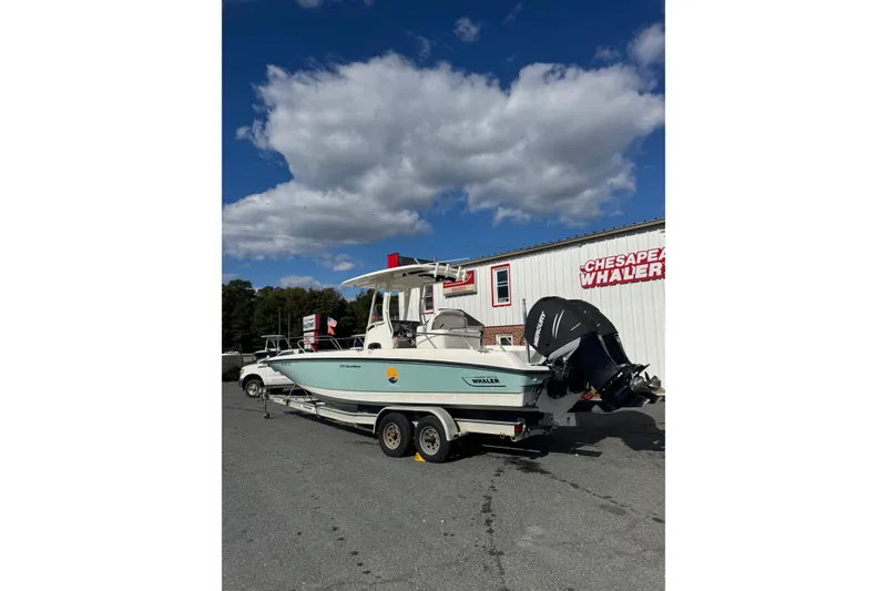 Slide: The Image of 2014 Boston Whaler 270 Dauntless boat on trailer, parked outside dealership under blue sky. - 13