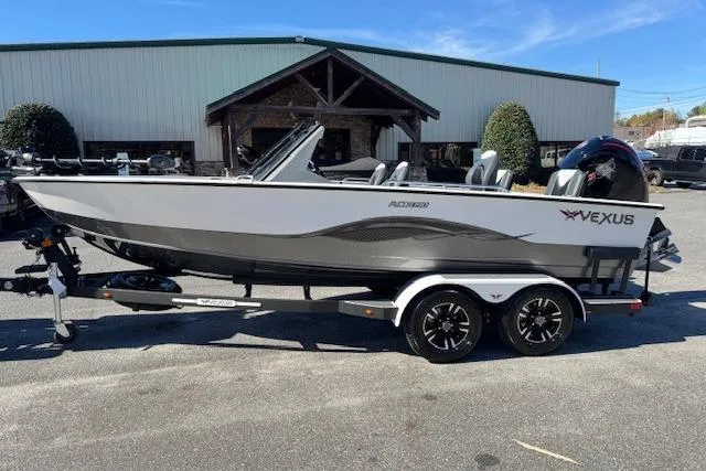 Slide: The Image of 2026 Vexus ADX 190 boat on trailer, parked outdoors near a building. - 2