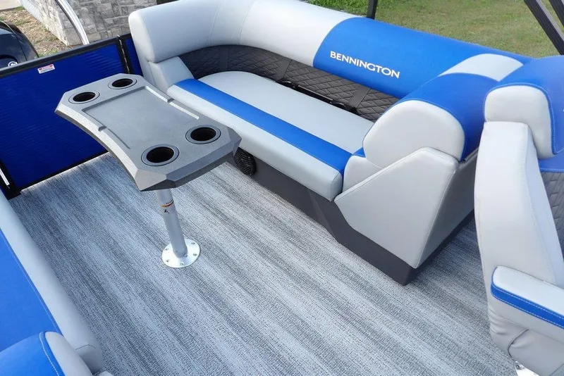 Slide: The Image of 2026 Bennington S Quad Bench 22 SSR interior with blue and gray seating and cupholder table. - 33