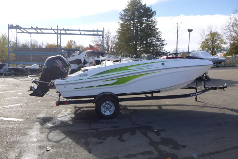 The Image of 2024 Tahoe T18 boat with green accents on a trailer in a parking lot. - 0