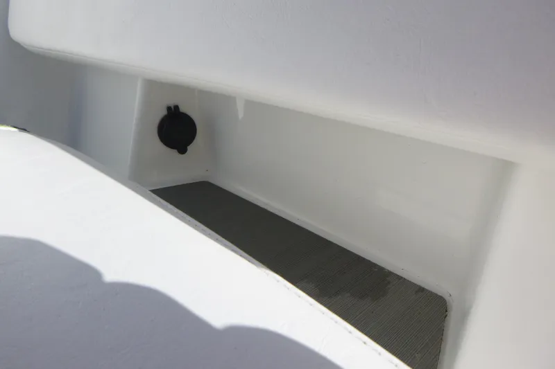 Slide: The Image of 2024 Tahoe T18 boat storage compartment with a black plug, white interior. - 23