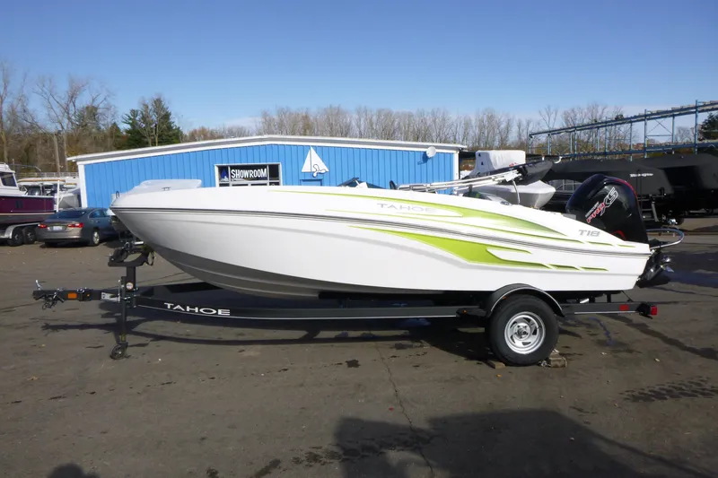 Slide: The Image of 2024 Tahoe T18 boat on trailer, displayed outdoors near blue showroom. - 5