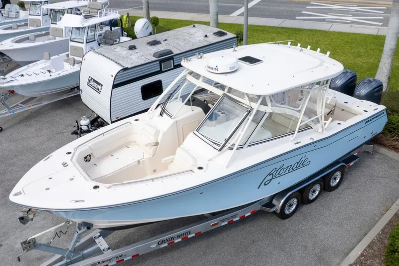 Slide: The Image of 2024 Grady-White Freedom 307 boat on trailer, parked near camper and other boats. - 1
