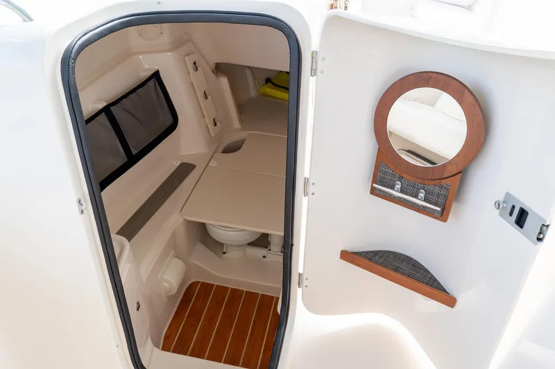 Slide: The Image of 2024 Grady-White Freedom 307 boat interior with compact bathroom and wooden accents. - 18