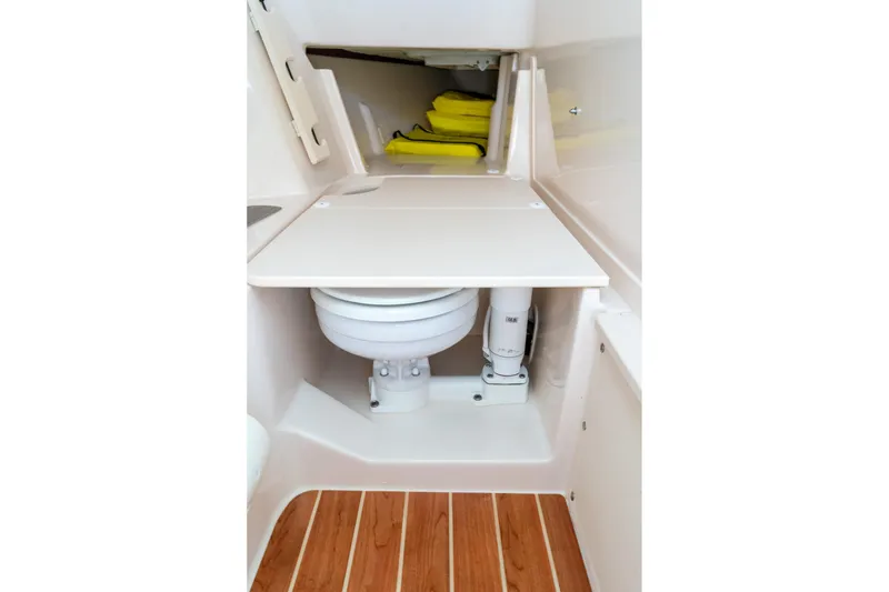 Slide: The Image of 2024 Grady-White Freedom 307 boat interior with compact marine toilet and wooden flooring. - 21