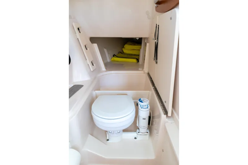 Slide: The Image of 2024 Grady-White Freedom 307 boat interior with compact marine toilet and storage area. - 22