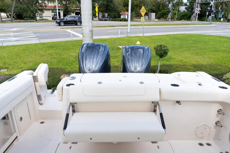 Slide: The Image of 2024 Grady-White Freedom 307 boat interior with dual outboard engines, parked near a road. - 46