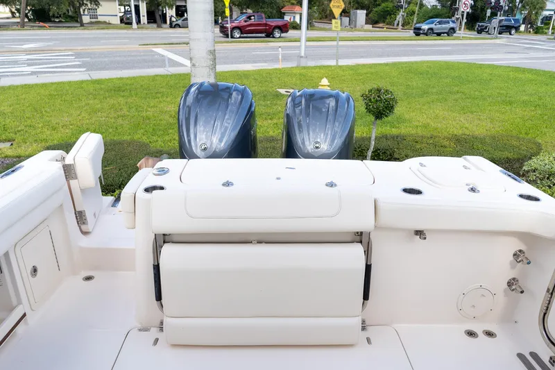 Slide: The Image of 2024 Grady-White Freedom 307 boat with dual outboard engines, docked near a grassy area. - 48