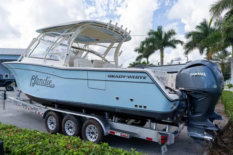 Slide: The Image of 2024 Grady-White Freedom 307 boat on trailer, featuring Yamaha engines, palm trees in background. - 5