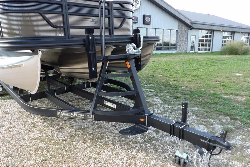 Slide: The Image of 2026 Bennington S Swingback 22 SSB on Bear Trailer, parked on gravel near a building. - 43