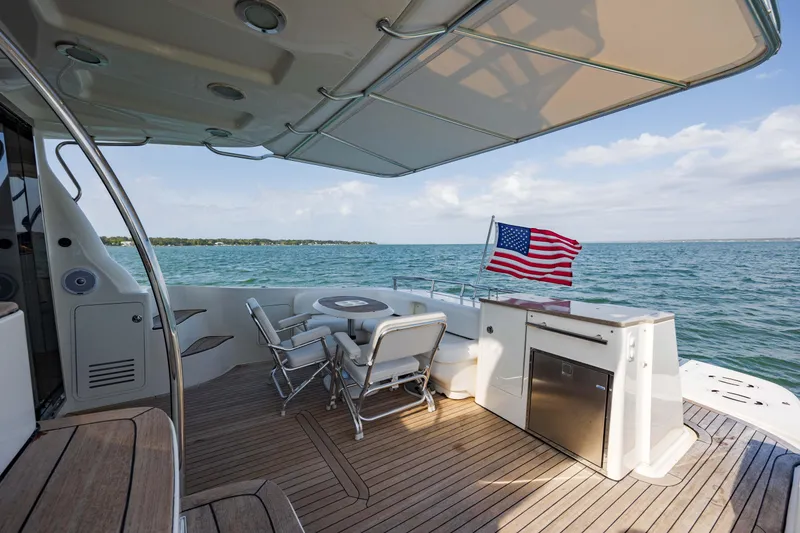 Slide: The Image of 2008 Sea Ray 52 Sedan Bridge yacht deck with seating, table, and American flag. - 22