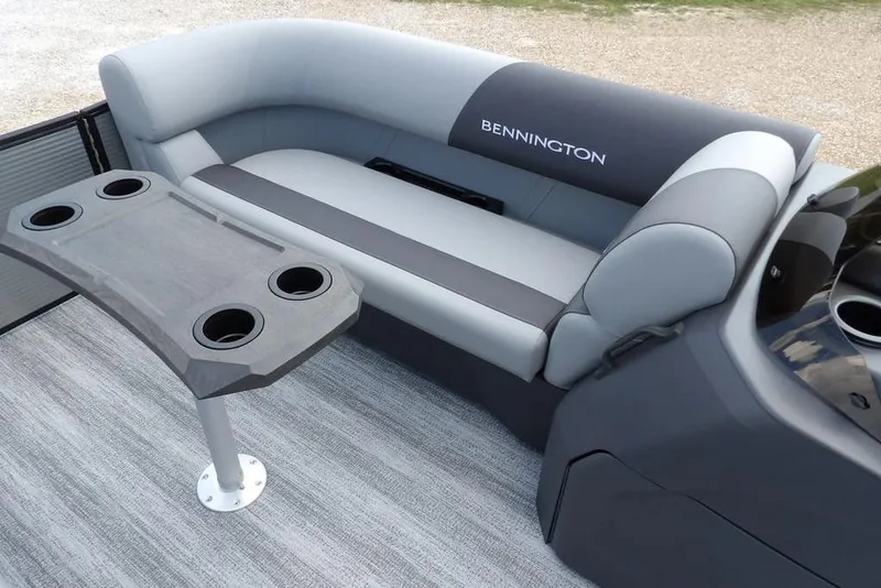 Slide: The Image of 2026 Bennington S Swingback 21 SSB boat interior with gray seating and cupholder table. - 15