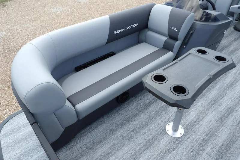 Slide: The Image of 2026 Bennington S Swingback 21 SSB boat interior with gray seating and cupholder table. - 8