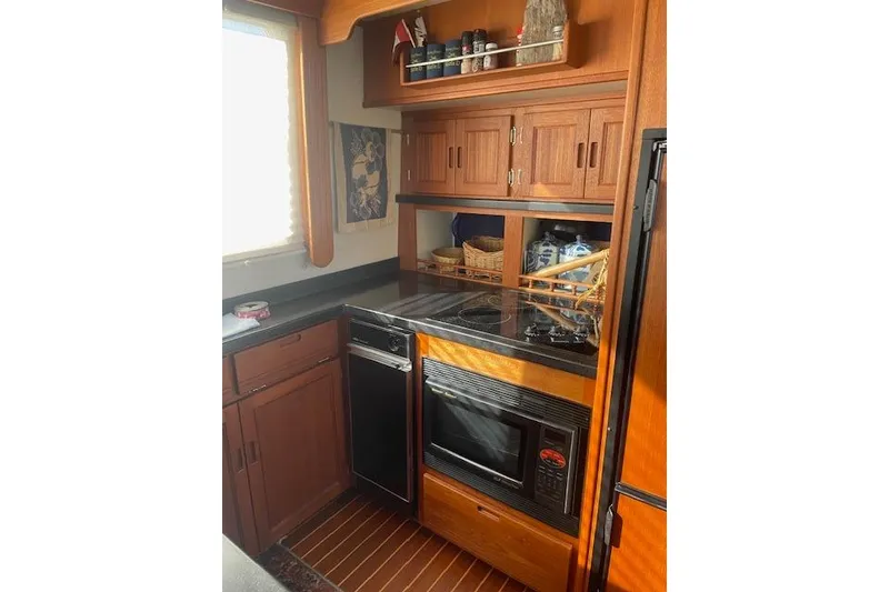 Slide: The Image of 2006 Nordic Tug 42 galley with wooden cabinetry, modern appliances, and ample storage space. - 28