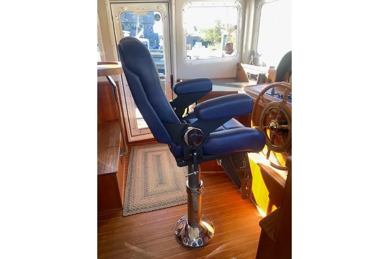 Slide: The Image of Captain's chair in 2006 Nordic Tug 42 boat interior, featuring blue upholstery and wooden flooring. - 37