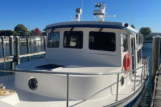 Slide: The Image of 2006 Nordic Tug 42 docked at a marina, featuring a classic design and safety equipment. - 4