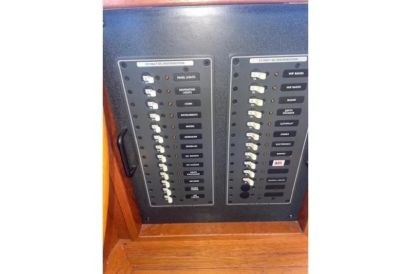 Slide: The Image of Electrical panel of a 2006 Nordic Tug 42 boat, featuring 12-volt DC distribution switches. - 43