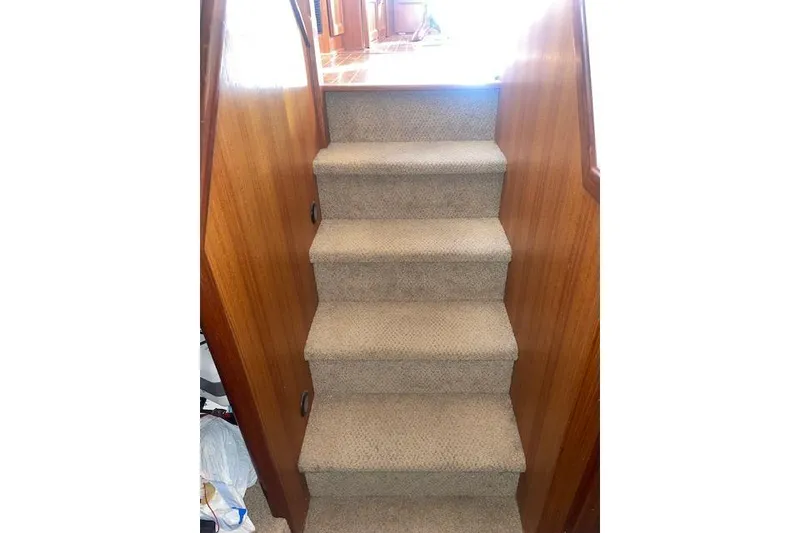 Slide: The Image of Carpeted stairs inside a 2006 Nordic Tug 42 boat, featuring wooden side panels. - 44