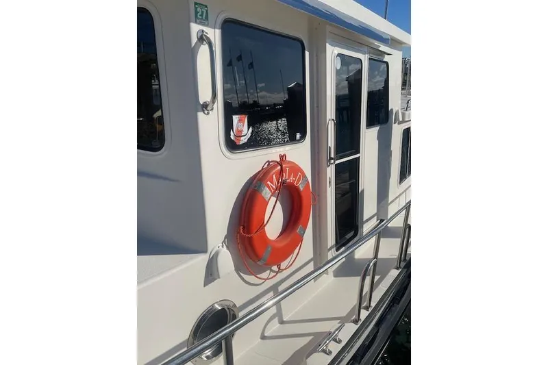 Slide: The Image of 2006 Nordic Tug 42 boat with life preserver on deck, docked in sunlight. - 5