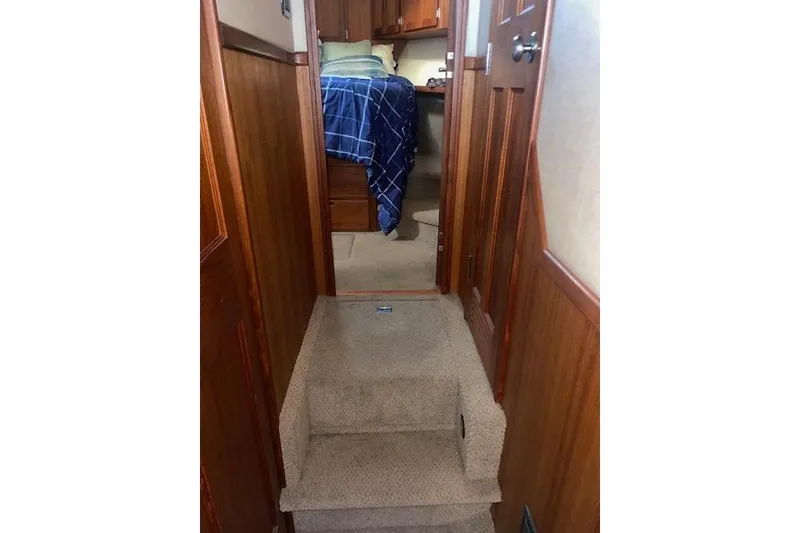 Slide: The Image of Interior of 2006 Nordic Tug 42, featuring carpeted stairs and cozy cabin with blue bedding. - 51