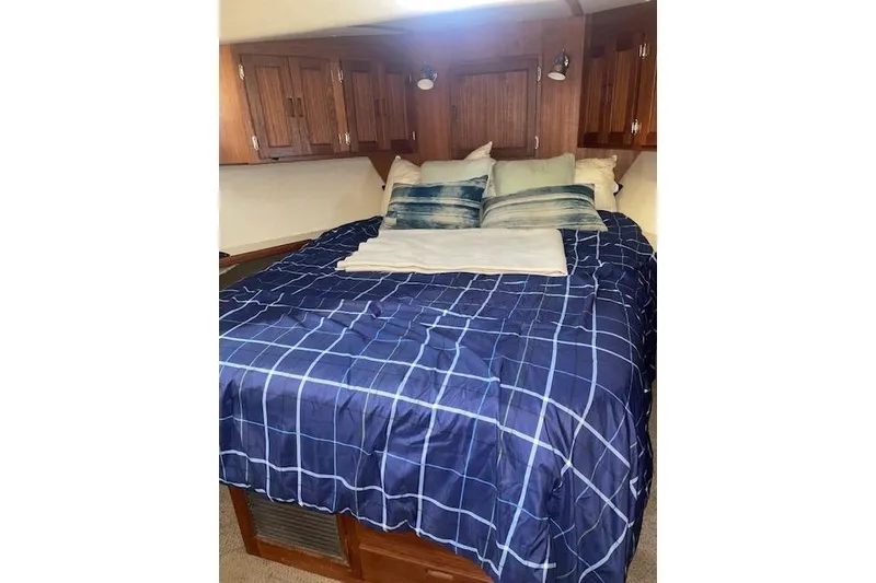 Slide: The Image of Cozy bedroom in 2006 Nordic Tug 42 with blue checkered bedding and wooden cabinets. - 52