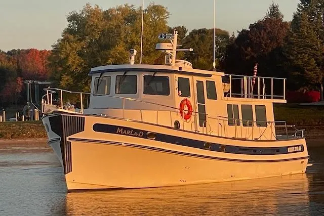 Slide: The Image of 2006 Nordic Tug 42 boat on calm water at sunset, surrounded by trees. - 7