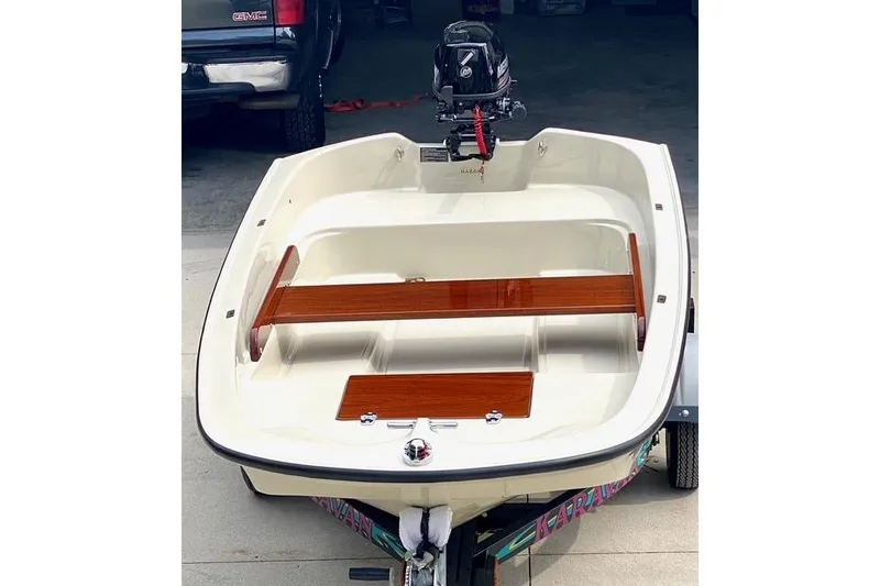 Slide: The Image of Small boat with wooden seats and outboard motor, parked on a trailer. - 74