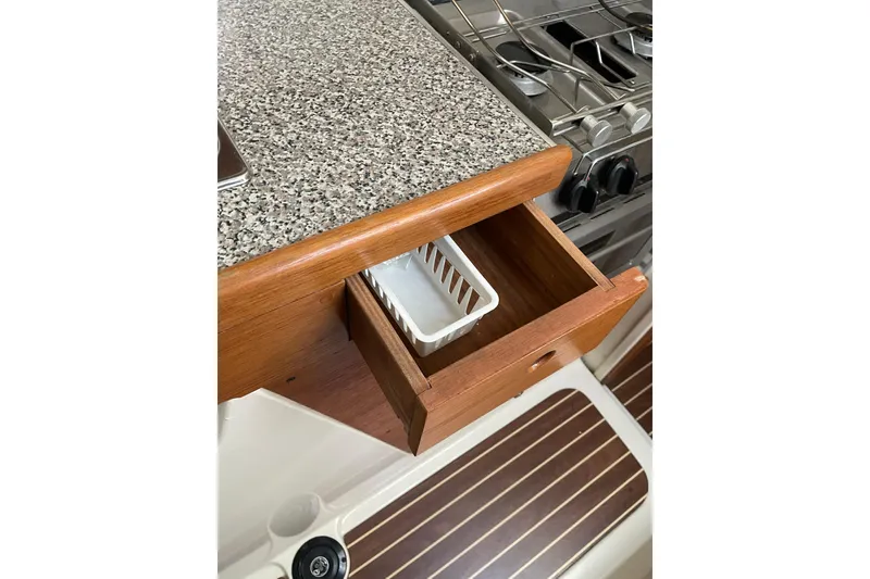 Slide: The Image of Open wooden drawer with white basket under granite countertop, near stove. PCI 105 MC, 2009. - 19
