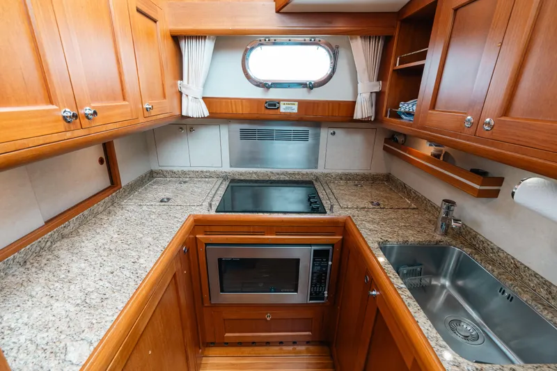 Slide: The Image of Luxurious 2011 Grand Banks 46 Eastbay SX yacht kitchen with granite countertops and wooden cabinetry. - 11