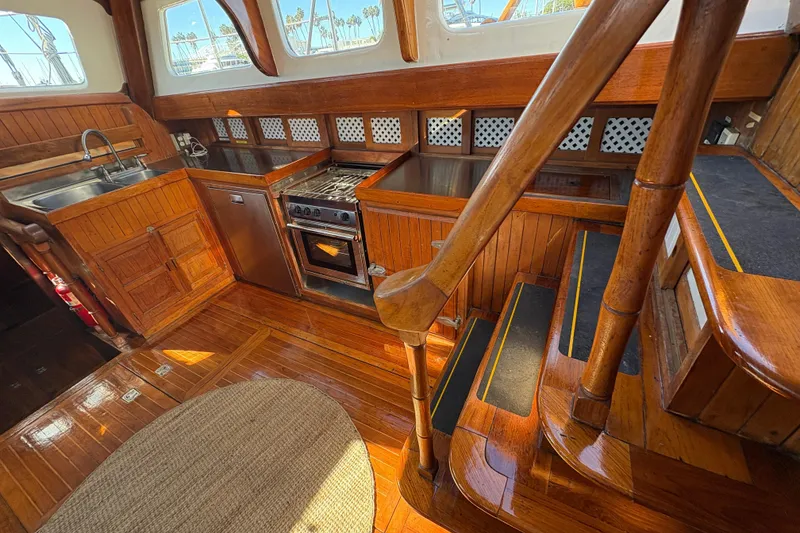 Slide: The Image of 1979 Formosa 51 yacht interior with wooden kitchen, stairs, and stainless steel appliances. - 28