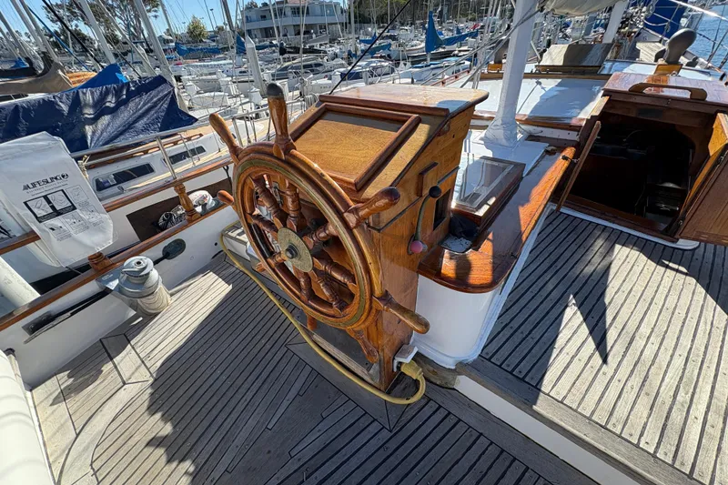Slide: The Image of Wooden helm of a 1979 Formosa 51 sailboat, docked in a marina. - 3