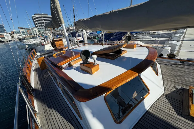 Slide: The Image of 1979 Formosa 51 sailboat with wooden deck, docked in a marina under clear blue skies. - 4