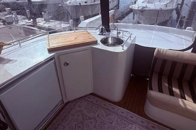 Slide: The Image of 2007 Navigator 58 yacht interior with kitchenette, featuring sink, cutting board, and seating area. - 15