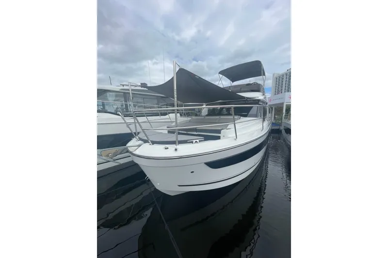 Slide: The Image of 2026 Jeanneau NC 1095 Fly Series 2 boat docked under cloudy skies. - 2